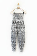 Black and white patterned pants hanging on a wooden hanger against a white wall.