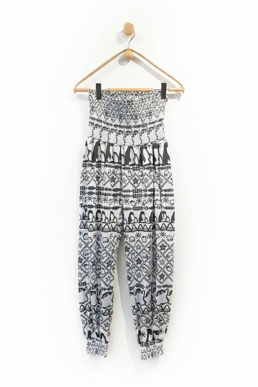 Black and white patterned pants hanging on a wooden hanger against a white wall.