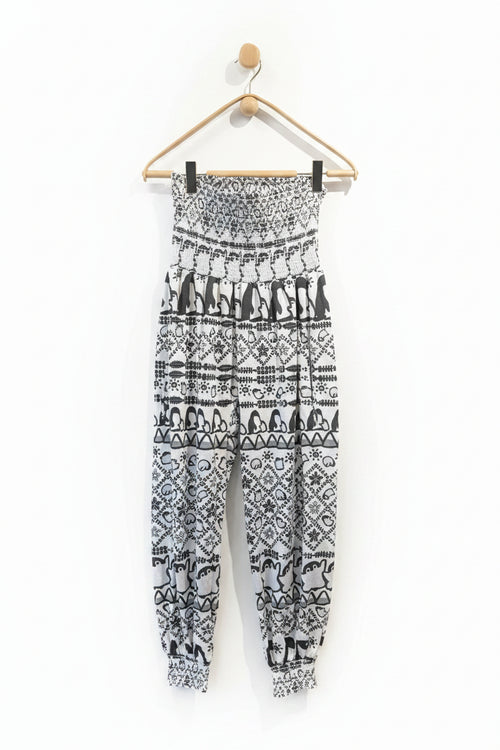 Black and white patterned pants hanging on a wooden hanger against a white wall.